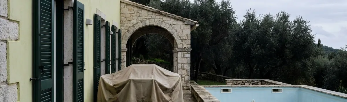 Κερκυραϊκό σπίτι κλειστό για τον χειμώνα: παντζούρια αμπαρωμένα, έπιπλα κάτω από καθαρά καλύμματα